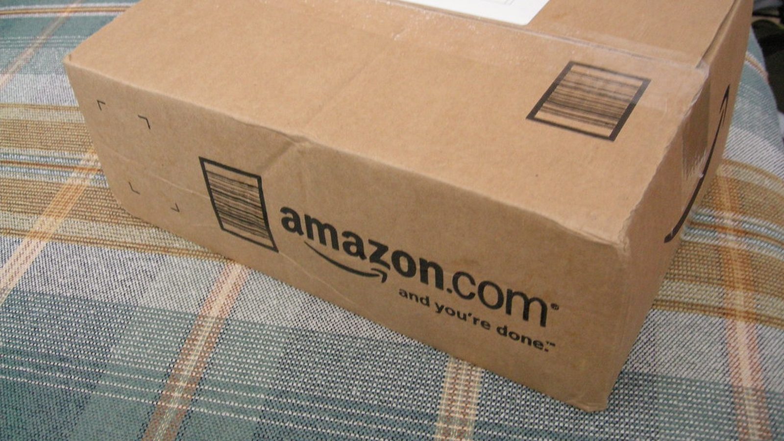 Open cardboard ecommerce box with dried flowers and forest green tissue on ivory linen