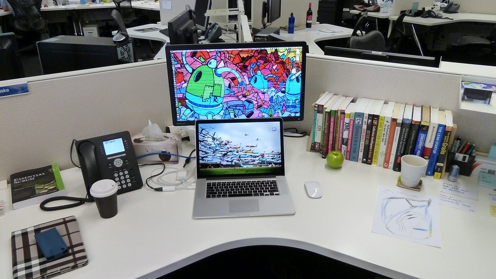 A hand holding a smartphone showing an email inbox above a light desk with a plant and a terracotta cup